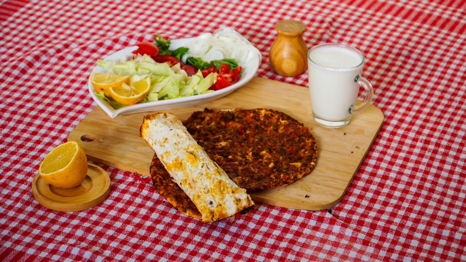 Eine lebendige türkische Mahlzeit mit Lahmacun, frischem Salat und Ayran, serviert auf einem Holzbrett.